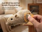 A plush toy mouse being held by a human hand, with overlaid text explaining how to activate it and an orange arrow graphic showing the twist mechanism. The background is a softly blurred indoor room.